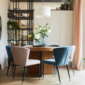 Stylish composition of elegant dining room interior design with velvet armchairs, design rounded wooden table and beautiful personal accessories. Glamour interior design inspiration. Template.